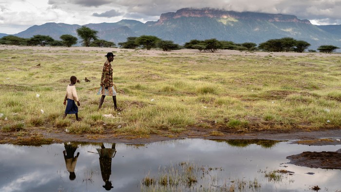 En mand og en dreng går langs en flod i Afrika