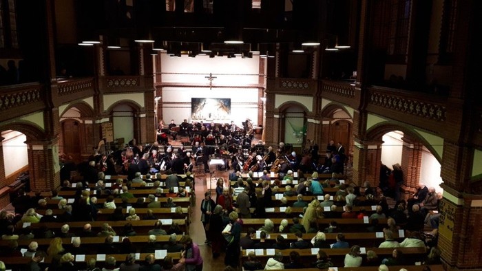 Große Kirche mit vielen Menschen und einem großen Kreuz an der Wand