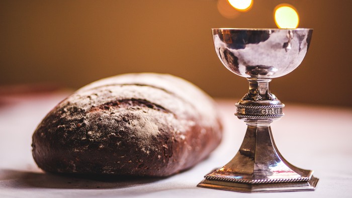 Silver chalice and dark bread on table