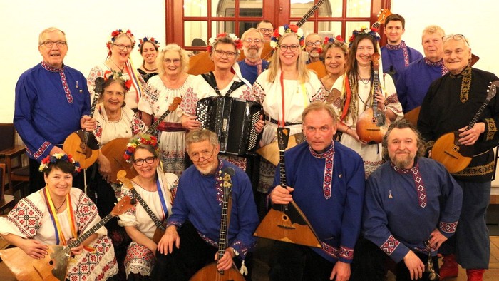 Traditionelt folkemusikorkester i farverige nationale dragter, der spiller på forskellige instrumenter sammen.