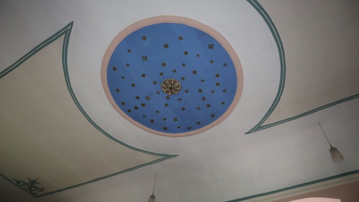 Eine blaue, runde Decke mit goldenen Sternen und einem zentralen Muster, umgeben von weiß-grünen Zierleisten.