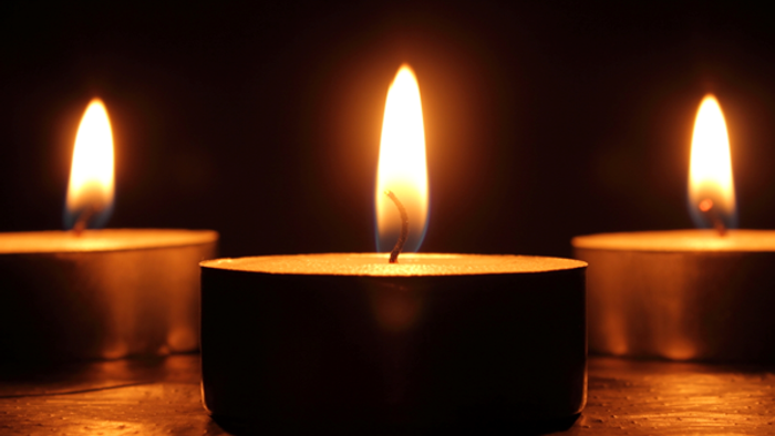 Three lit candles in dark setting.