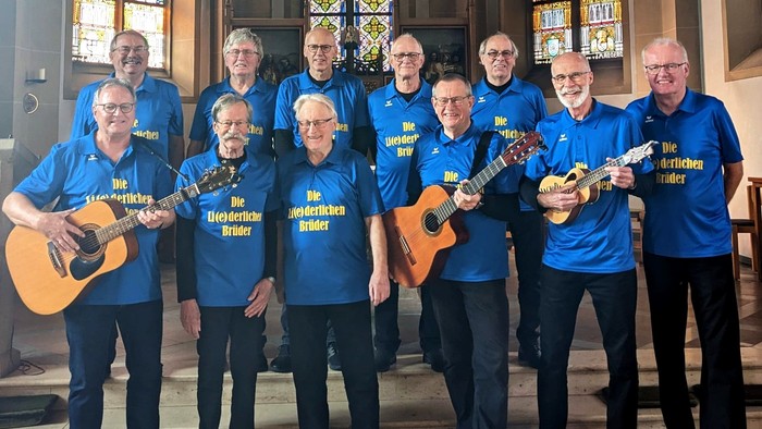 Eine Gruppe von Menschen in blauen T-Shirts spielt Gitarren und Ukulelen in einer Kirche.