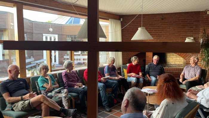 En gruppe af mennesker sidder i en lounge og diskuterer.