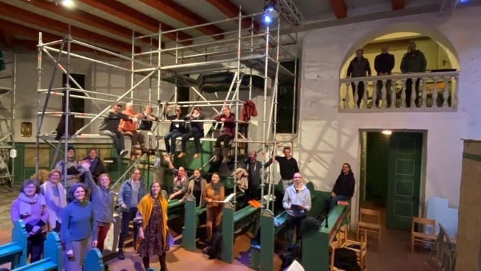 Eine Gruppe von Menschen posiert vor einer historischen Maschine in einem Museum.