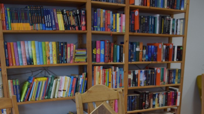 Holztresen mit Blumen und Schmuck, Bücherregal im Hintergrund
