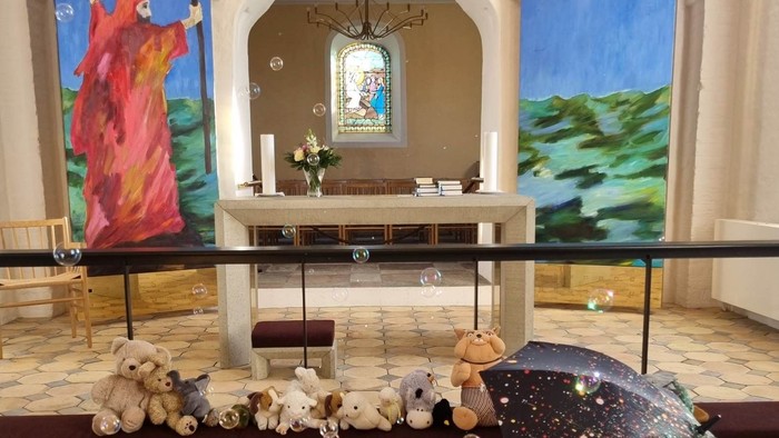 En kirkeindretning med malerier, bjørnefigurer og lysstake.