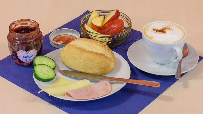 Frühstücksbuffet mit Brot, Käse, Marmelade, Obst und Kaffee.