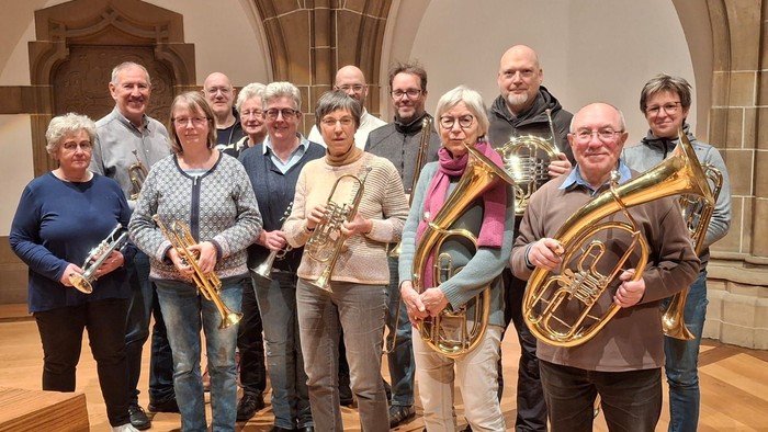 Ein Gruppe von Musikern posiert mit ihren Instrumenten in einem großen Raum