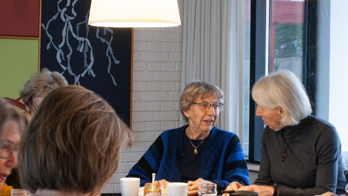 En gruppe pensionister sidder ved et bord i et café og spiser morgenmad.