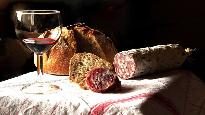 Wein, Brot und Wurst auf Tischdecke