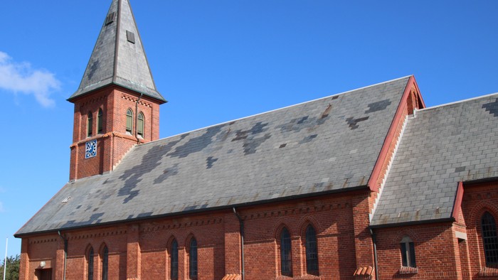 Røde kirke med tårn og spids tak.