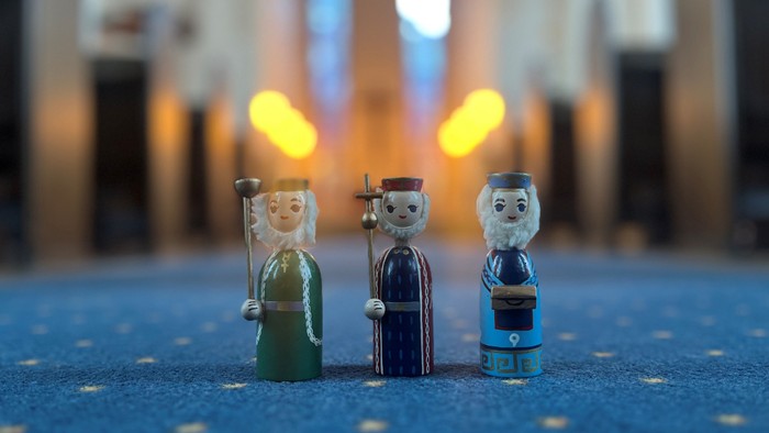 Tre træfiguriner står på blåt tæppe.