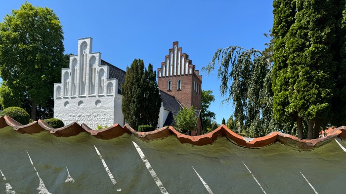 Oversvømmet kanal med historiske bygninger og buede kajmure delvist under vand, omgivet af grønne områder.