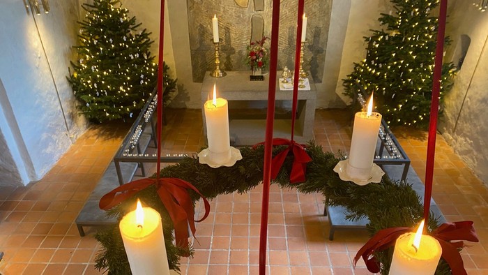 Julekrans med stearinlys og sløjfer i et flisebelagt rum med juletræer