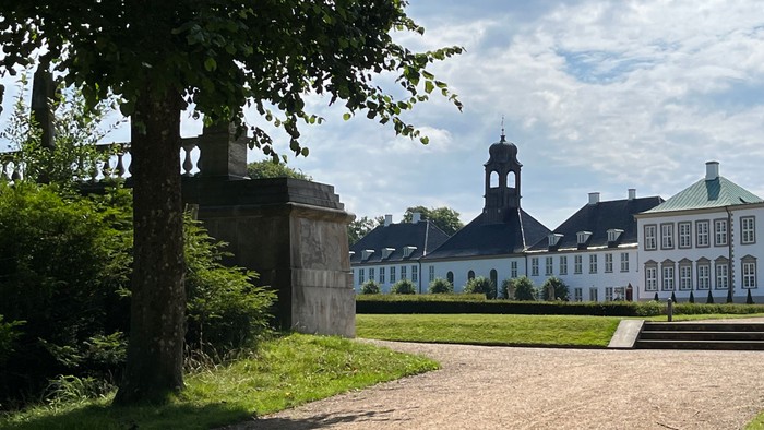 Elegant historisk palads omgivet af frodig grønne områder og en klar himmel.