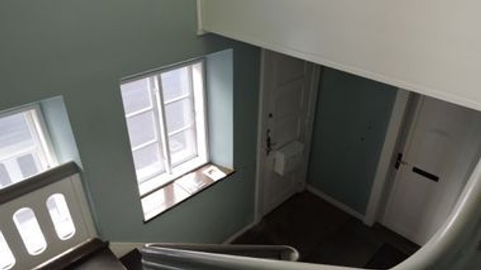 Stigeop ad til et lille rum med vindue og dør.