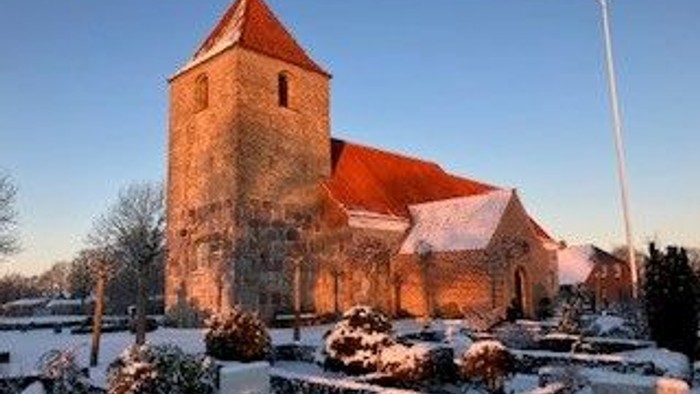 En kirke med røde tag og tårn i sneklædt landskab