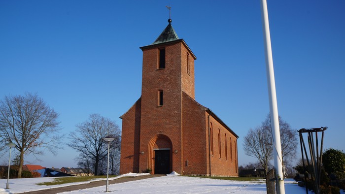 En rød kirke med tårn i snødekt landskab
