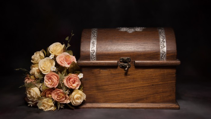 Small brown casket next to some roses.