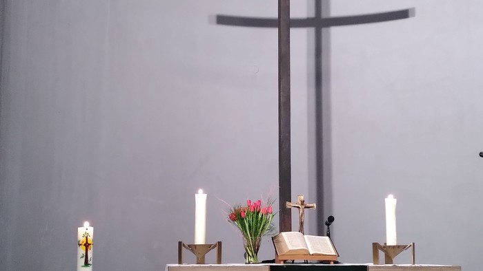 Ein Altar in einer Kirche mit Kreuz, Kerzen und Blumen