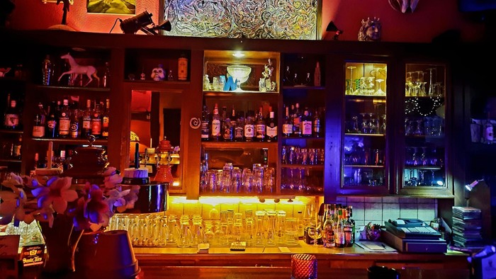 Lebendige Theke voller Flaschen, Dekorationsgegenstände und beleuchteter Regale.