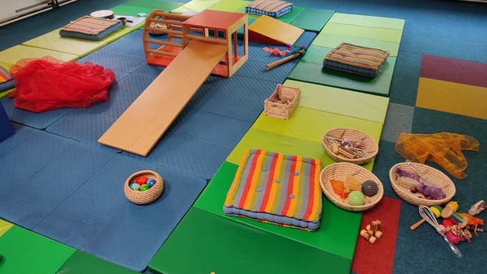 Ein Raum mit Matten ausgelegt auf denen sich Spielzeug für kleine Kinder befindet.