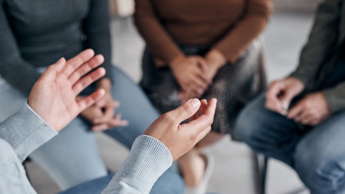 Eine Gruppe von Menschen sitzt im Kreis und hält sich an den Händen.
