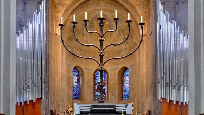 Innenraum einer Kirche mit großem Leuchter und farbenfrohen Fenstern