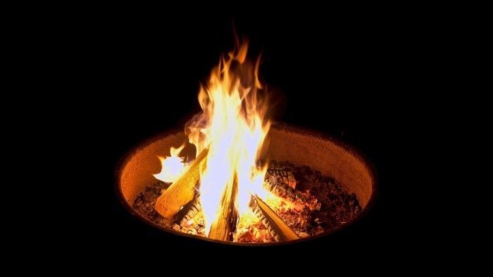 Lebhafte Lagerfeuerflammen, die nachts hell in einer Feuerstelle lodern.