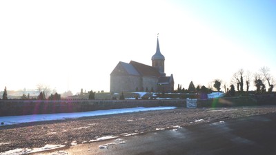 En kirke med tårn ved en frossen sø.