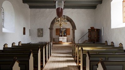 Indenrigsrom i kirke med bænke og lysstake