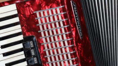 Et rødt akkordeon med sorte nøgler og håndtag.
