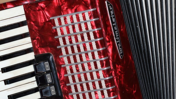 Et rødt akkordeon med sorte nøgler og håndtag.