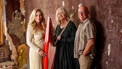 Tre personer poser sammen, to holder musikinstrumenter