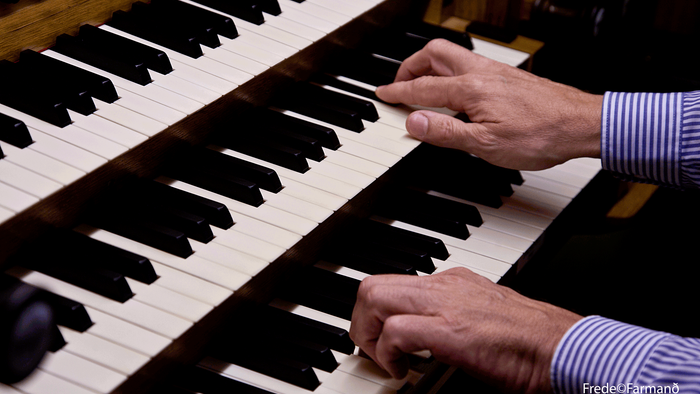 En person, der spiller på tangenterne af et stort pibeorgel med begge hænder.