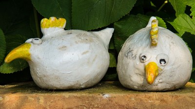 Zwei Keramiktöpfe in Form von Hühnern auf einer Mauer
