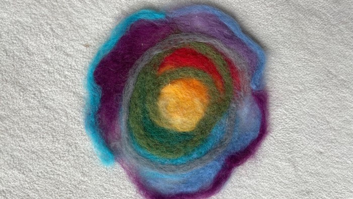 Lebendige, wirbelnde Faser-Kunst, die einer farbenfrohen Galaxie oder einem Nebel in aufwendigem Nadelfilz-Design ähnelt.