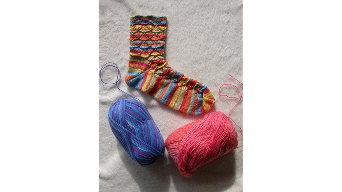 Gestrickte Socke mit buntem Garn und Stricknadeln