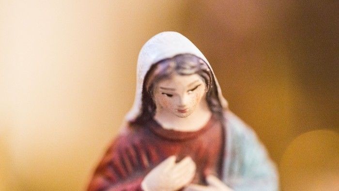 En lille statue af en kvinde med hvid skjorte og rød kappe.