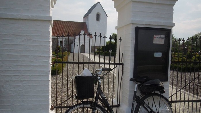 Cykel parkeret foran hvid bygning.