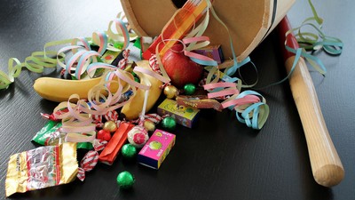 En sort flade med papirfjer, chokolade, nødder og en træknogt.