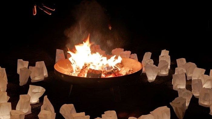 Holz brennt in einer Feuerschale umringt von kleinen Lichtern.