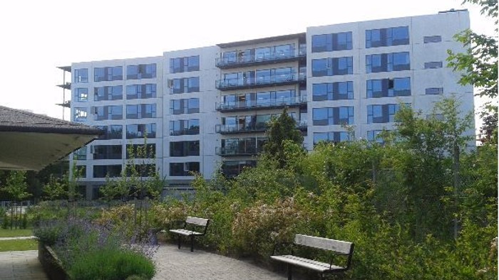 En moderne bygning med mange vinduer og en træstue med bænke.