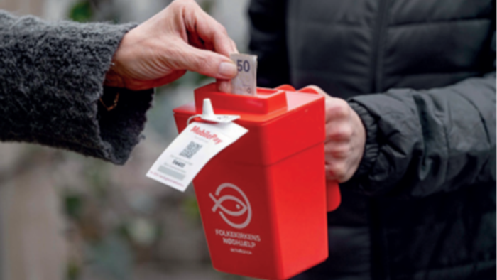 En person giver penge til en rød samlingskasse.