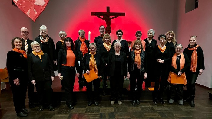Eine Gruppe von Menschen posiert vor einem Kreuz in einer Kirche