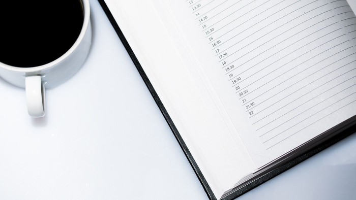 En blank opskrivet bog og en kaffe-tasse på en skrivebord