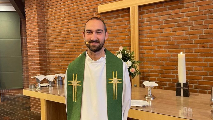 Mand i kirkeklæder foran alter.