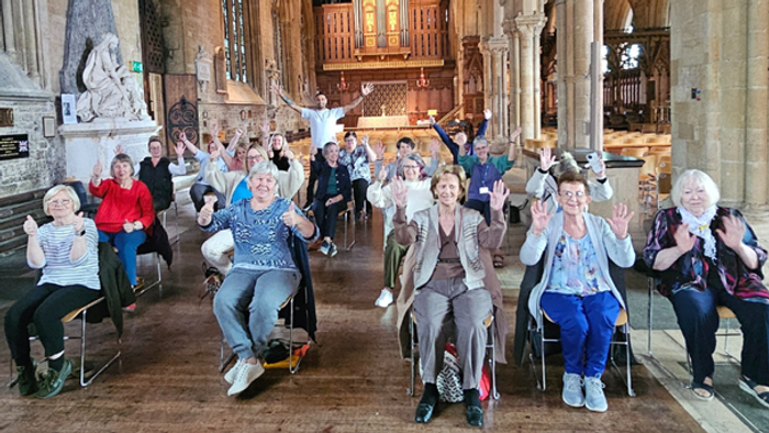Group of people sitting in a large room, some clapping and smiling.