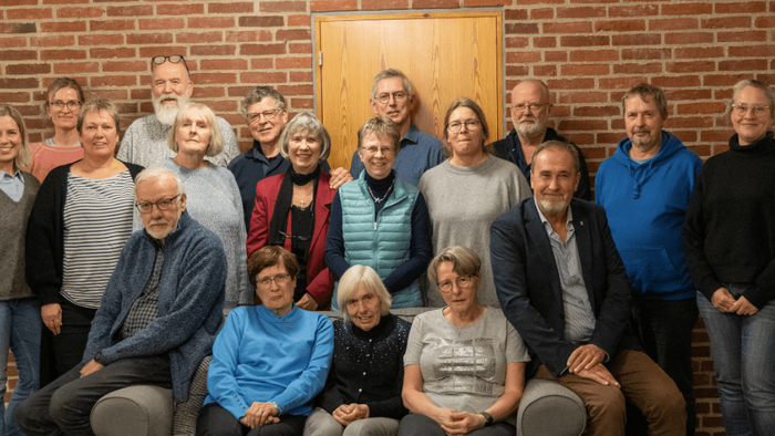 Gruppe af mennesker, der poser sammen foran en murstensvæg.